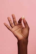 Dark Skinned Hand Holding A Pill