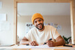 © BONNINSTUDIO/Stocksy - Smiling black male illustrator drawing on paper