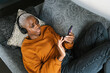© Ezequiel Giménez/Stocksy - Female using smartphone while chilling on couch