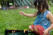 Little Kid Playing In Sprinkler