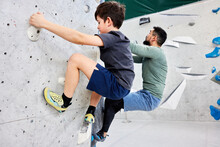 Boy And Dad Climbing In A Bouldering Gym