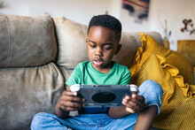 Little Boy Playing With A Game Console At Home