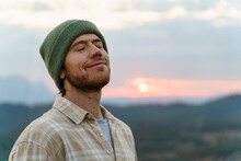 Portrait Of Happy Man In Nature At Sunset With Closed Eyes