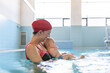 © Santi Nuñez/Stocksy - Mother teaching baby swimming pool