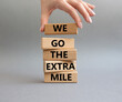 We go the extra mile symbol. Wooden blocks with words 'We go the extra mile'. Beautiful grey background. Businessman hand. Business and 'We go the extra mile' concept. Copy space.