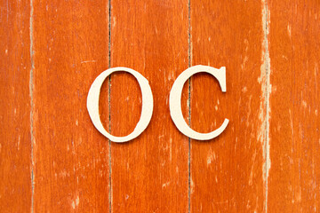 Alphabet letter in word OC (Abbreviation of opportunity cost or original content, character) on old red color wood plate background