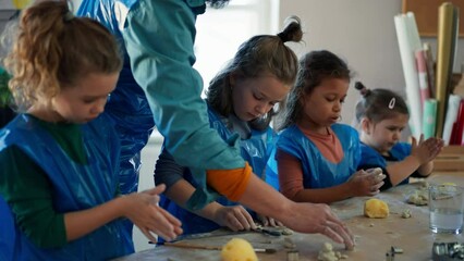 Wall Mural - Group of little kids with teacher working with pottery clay during creative art and craft class at school.