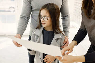 Optometrist helping family choosing glasses in optics store