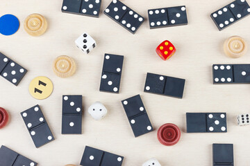 Wooden checkers, dice, chips and dominoes on table. View from above.