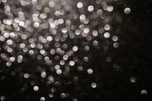 Black White Bokeh. Bokeh Lights On A Black Background, Shot Of Flying Drops Of Water In The Air, Defocal Drops Of Water Levitation On A Dark, Blurry. Black And White Blurred Bokeh Lights Background