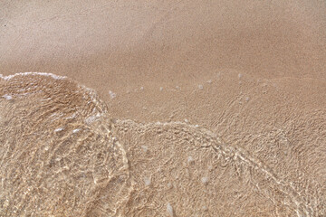 Wall Mural - Empty sandy beach in Greece, close up top view. Sea water touch wet sand, copy space. Summer holiday