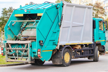 Fototapete - A garbage truck picks up garbage in a residential area. Loading mussar in containers into the car. Separate collection and disposal of garbage. Garbage collection vehicle.
