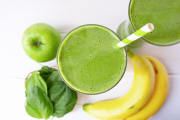 Wall Mural - Banana mix spinach apple smoothie green juice beverage healthy the taste yummy in glass for on white wood background from the top view.