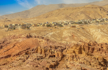 Wall Mural - View to the ancient Nabataean Moghar Annasara tombs with Wadi Musa town in the background, Petra, Jordan