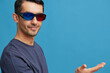 © SHOTPRIME STUDIO - portrait man Cheerful man in cinema glasses in a t-shirt blue background