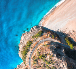 Wall Mural - Aerial view of mountain road near blue sea with sandy beach at sunset in summer. Oludeniz, Turkey. Top view of road, trees, azure water, mountain. Beautiful landscape with highway, rocks, sea coast
