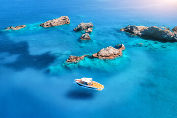 Wall Mural - Aerial view of speed boat on blue sea at sunset in summer. Motorboat on sea bay, rocks in clear turquoise water. Tropical landscape with yacht, stones. Top view from drone. Travel in Oludeniz, Turkey