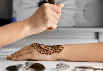 Wall Mural - Mehndi master drawing henna tattoo on female hand in salon