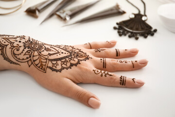 Wall Mural - Female hand painted with henna on light background, closeup