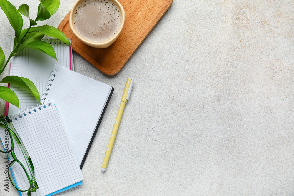 Notebooks, cup of coffee, glasses and pen on light background, top view