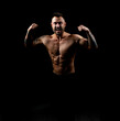 © A Stock Studio - Strong male bodybuilder with a naked torso, shows the relief of his muscles on his arms and body, standing against a black background. Champion.