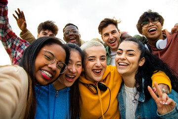 Group of multiracial teen college friends having fun outdoors. Happy people taking selfie.