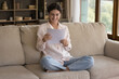 © fizkes - Happy woman review printed paper document, read written information smile feel satisfied, learn personal finance bank statement glad about paid debt confirmation sit on sofa at home, good news concept