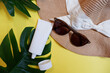 Summer is coming frame. Vacation beach accessories on yellow color background. Flat lay with copy space for your promo text. Top view Tropical leaves, sunblock tube, sunglasses and hat.