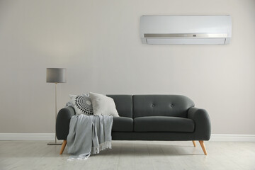 Canvas Print - Modern air conditioner on white wall in room with stylish grey sofa