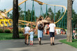 © somemeans - Mother with three children goes to an amusement park. Back view. Family goes to riding the roller coaster.