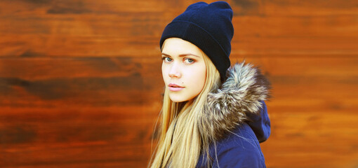 Wall Mural - Portrait of beautiful blonde young woman wearing hat and jacket in the city