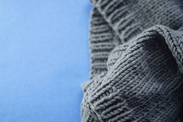 Wall Mural - Cozy gray knitted sweater on blue table, copy space