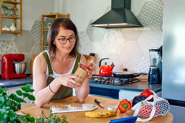 Wall Mural - Woman enjoying her healthy breakfast checking on her smart phone at home. Brunch with puffed corn cakes, peanut butter and banana. Protein diet concept.