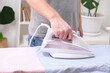 © detry26 - A man is ironing a shirt with an electric iron on an ironing board.