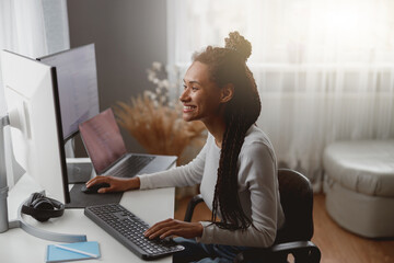 Wall Mural - smiled cheerful female web expert sitting at desk in living room coding on computer
