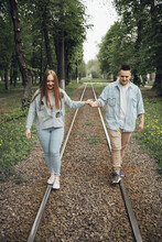 A Couple In Love Walks Fooling Around On Tram Tracks