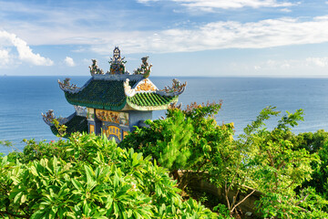 Wall Mural - Tile roof of Buddhist temple among foliage on sea background