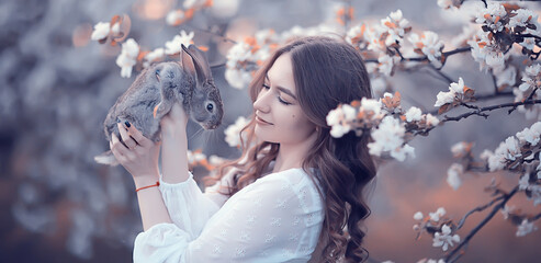 easter bunny in the hands of a beautiful girl, spring, april in a blooming garden, portrait of a woman