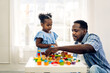 © Art_Photo - Portrait of happy love black family african american father with little girl smiling activity learn and skill brain training play with toy build wooden blocks board education game at home.father day