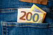 A 200 Euro banknote with the Euro symbol in the pocket of a pair of jeans. Concept about savings, wealth, profits, investments or the use of cash.