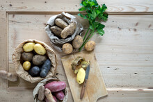 Parsley And Different Varieties Of Raw Potatoes On Rustic Wooden Background