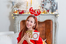 Happy Woman Wearing Christmas Headdress Holding Greeting Cards At Home