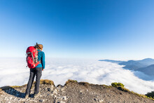 Germany, Bavaria, Female Hiker Standing On Mountaintop Admiring Fog Shrouded Peaks Of Bavarian Prealps