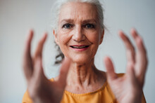 Happy Senior Woman Gesturing Against White Background