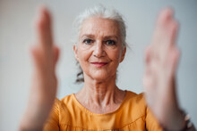 Senior Woman With Gray Hair Gesturing With Hand Against White Background