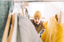 Young Man Searching For Warm Clothes In Wardrobe