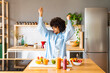 © Westend61 - Happy woman with arms raised dancing in kitchen at home