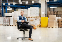 Businessman With Legs Crossed At Knee And Laptop In Factory