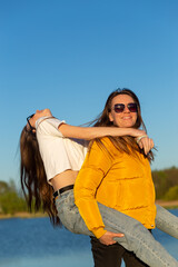 Wall Mural - Playful mother giving daughter piggy back ride at spring lake shore.