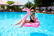 © artiemedvedev - Hot slim woman in bikini chilling with cocktail on inflatable pink flamingo float at swimming pool. Fit girl in swimwear lies in the sun and drinks on floaty. Pretty female on tropical vacation.